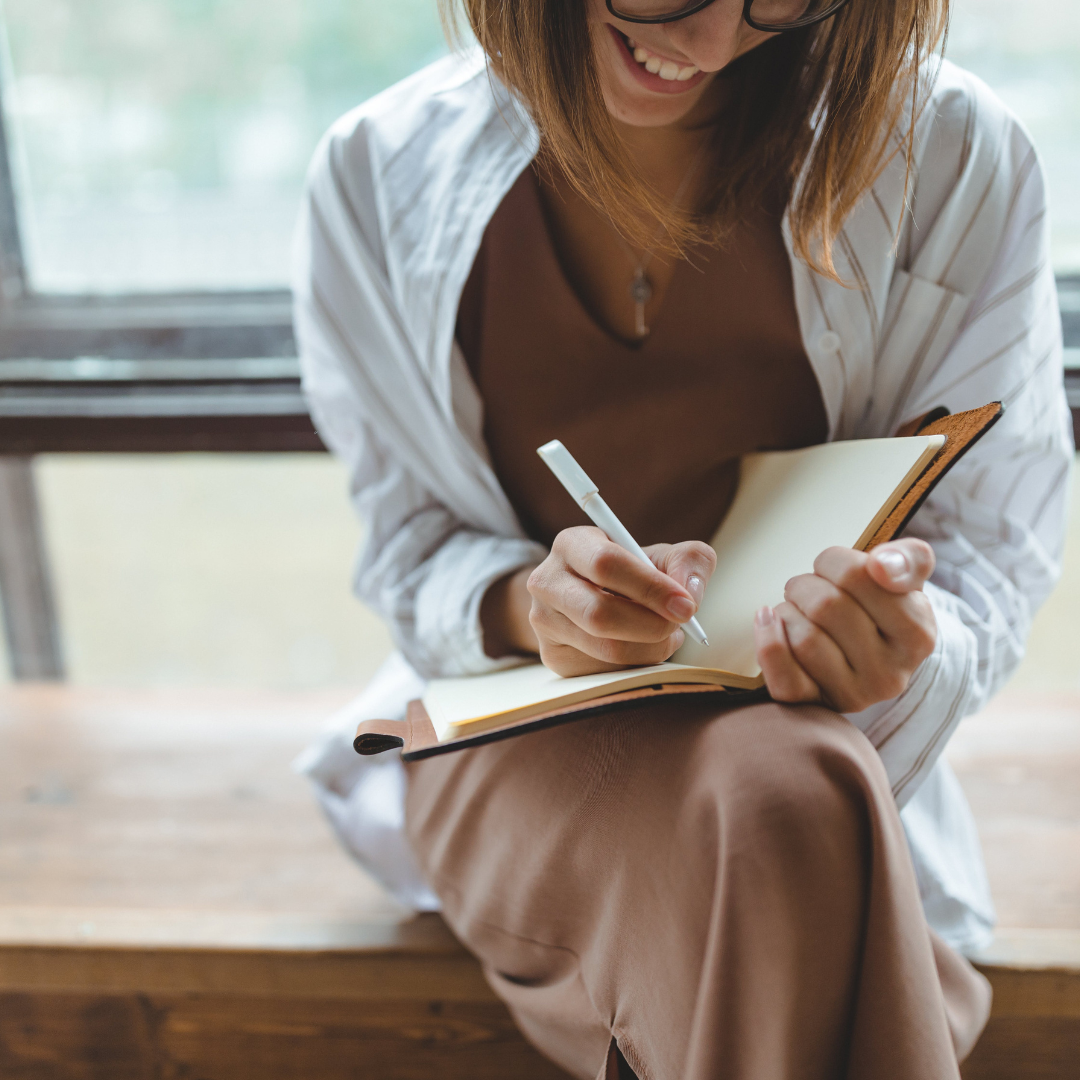 Smiling woman writing in a journal.